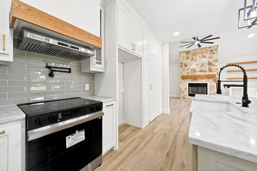 Contemporary kitchen featuring white cabinetry, light countertops, and wood-finish flooring Contemporary kitchen featuring white cabinetry, light countertops, and wood-finish flooring