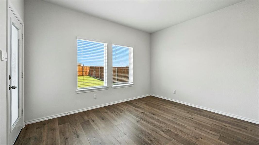 Spare room featuring dark wood-type flooring and baseboards
