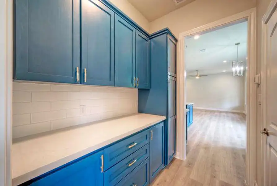 Kitchen with blue cabinetry, light wood-type flooring, decorative backsplash, and light countertops