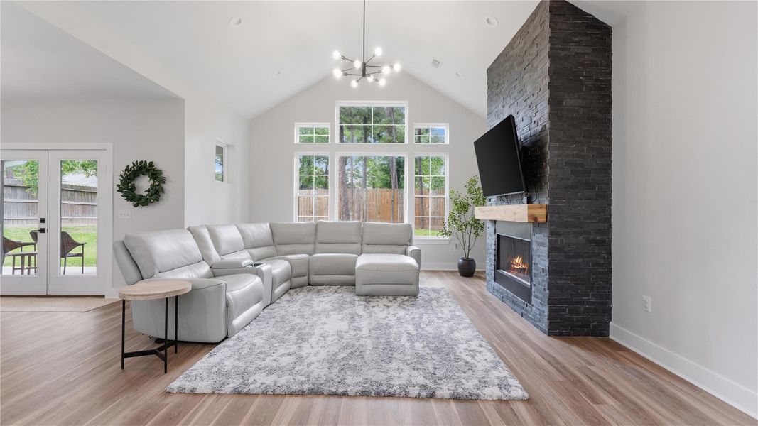 This living room has faulted ceilings, bright lighting and floor to ceiling fireplace.