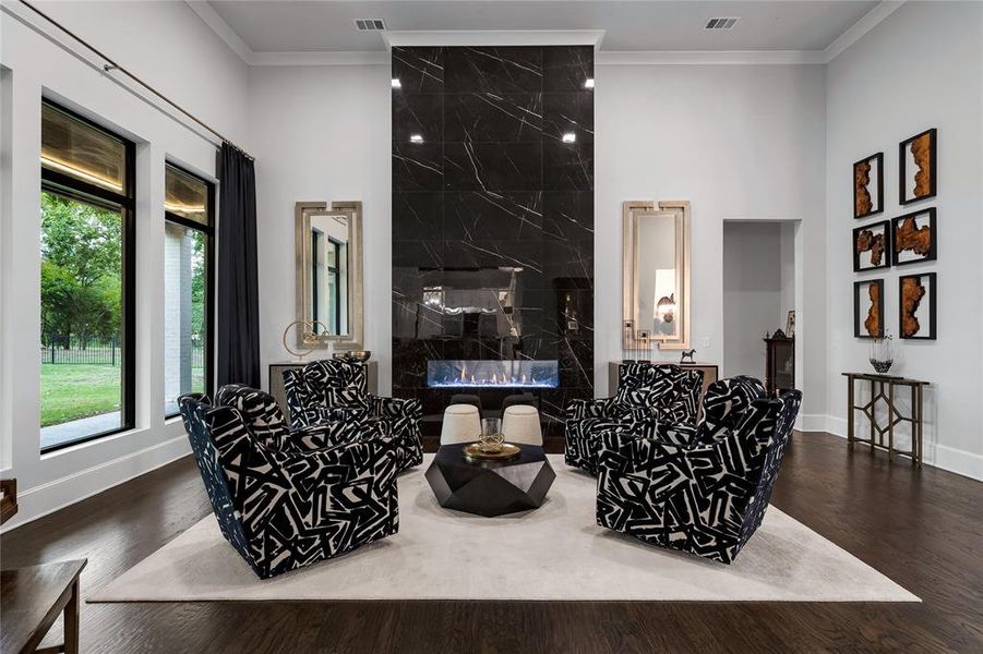 Living room featuring a high end fireplace, dark hardwood / wood-style floors, a wealth of natural light, and ornamental molding