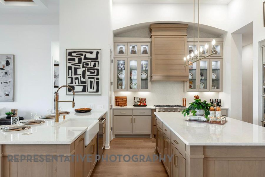 Kitchen featuring a kitchen island, light wood finished floors, ventilation hood, arched walkways, and light stone countertops Kitchen featuring a kitchen island, light wood finished floors, ventilation hood, arched walkways, and light stone countertops