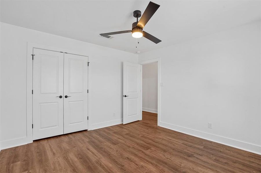 Unfurnished bedroom with a closet, a ceiling fan, baseboards, and wood finished floors