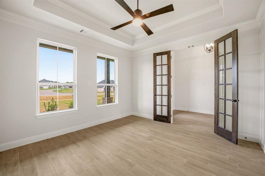 Unfurnished room with french doors, wood tiled floors, ceiling fan, a raised ceiling, and crown molding