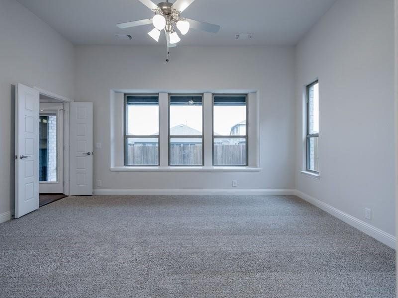 Carpeted empty room featuring ceiling fan and a healthy amount of sunlight