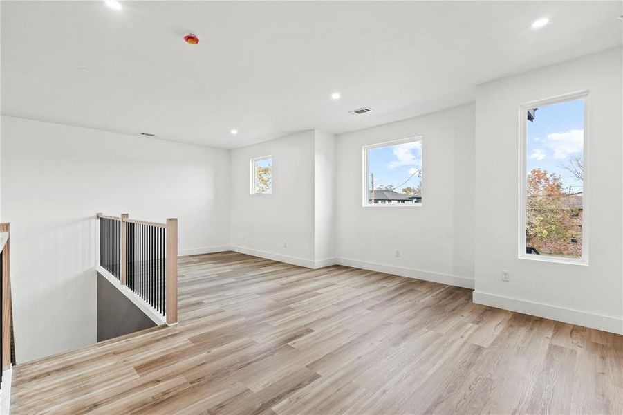 Spare room with light wood-style floors, plenty of natural light, and recessed lighting