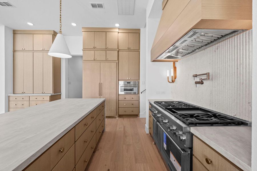 Close-up of the kitchen's premium gas range, custom hood, and detailed cabinetry.