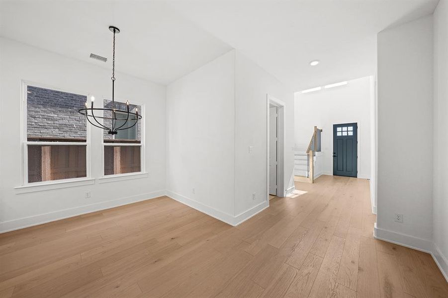 Unfurnished dining area featuring stairs, light wood-style floors, a chandelier, and recessed lighting