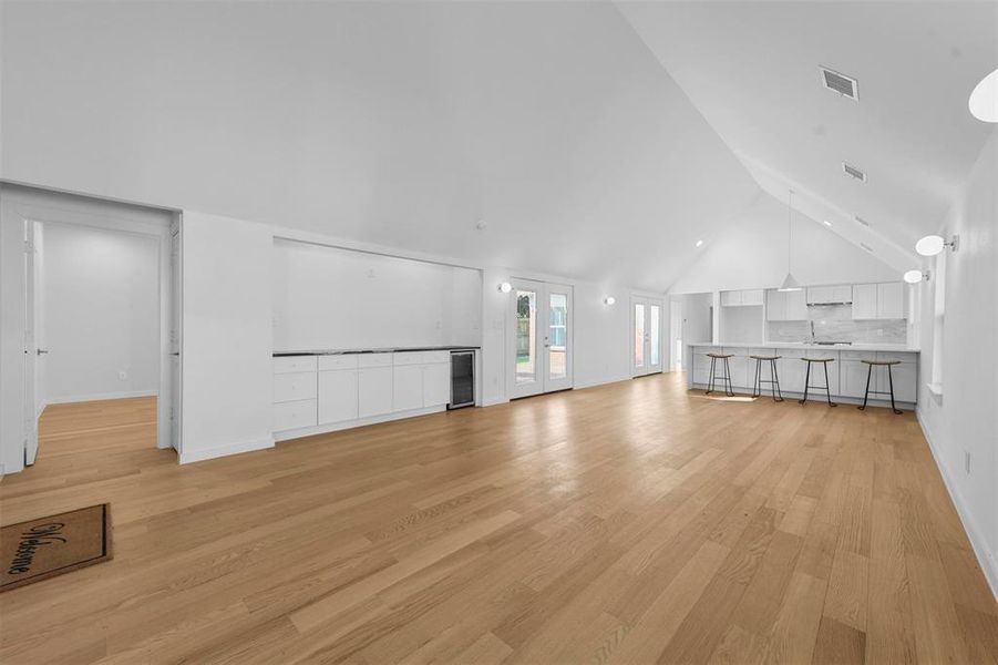 Unfurnished living room featuring high vaulted ceiling and light hardwood / wood-style flooring