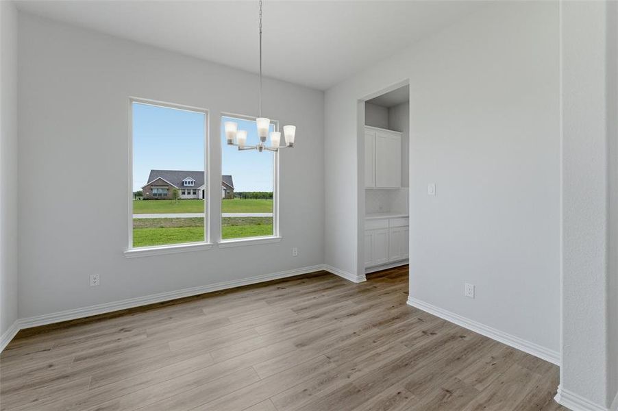 The property features light wood-look flooring, multiple windows providing natural light, a contemporary ceiling light fixture, and a built-in cabinet with white doors