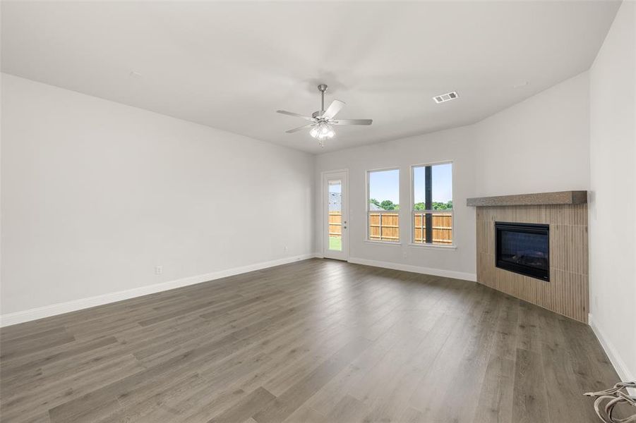 Unfurnished living room featuring a fireplace, a ceiling fan, and wood finished floors Unfurnished living room featuring a fireplace, a ceiling fan, and wood finished floors