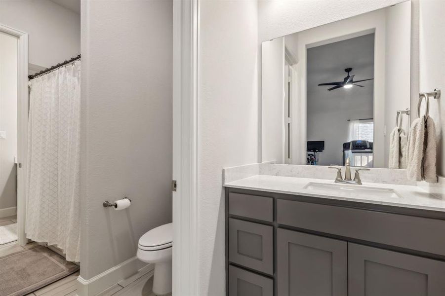 Bathroom with ceiling fan, vanity, walk in shower, and toilet