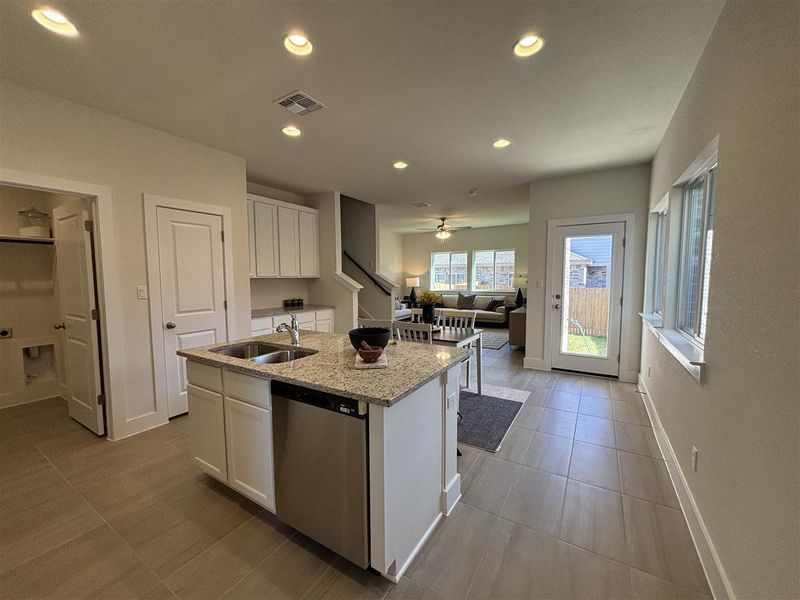 Kitchen featuring sink, white cabinets, stainless steel dishwasher, and a kitchen island with sink