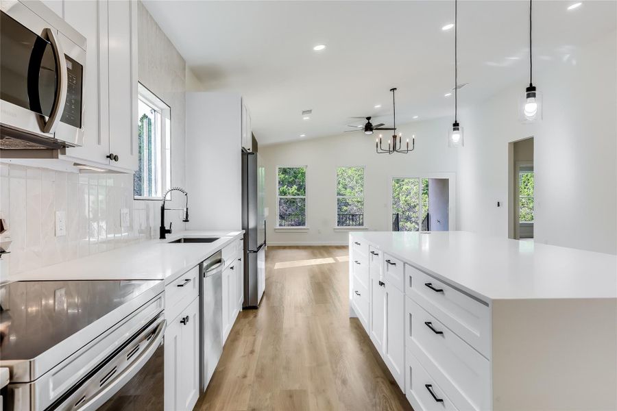 Kitchen with appliances with stainless steel finishes, light wood-style floors, decorative backsplash, light countertops, and recessed lighting Kitchen with appliances with stainless steel finishes, light wood-style floors, decorative backsplash, light countertops, and recessed lighting