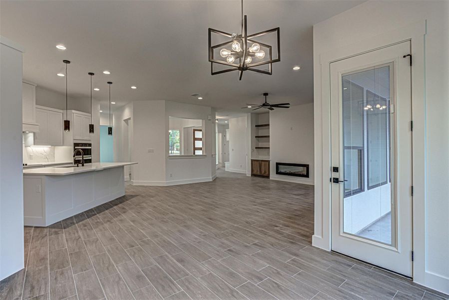 Living room with a chandelier, a fireplace, wood tiled floors, recessed lighting, and a ceiling fan Living room with a chandelier, a fireplace, wood tiled floors, recessed lighting, and a ceiling fan