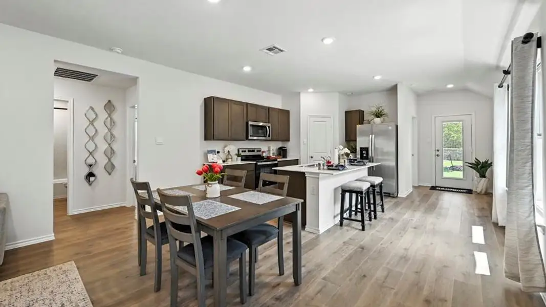 Open-concept living space featuring wood-finish flooring, recessed lighting, and a kitchen island with seating