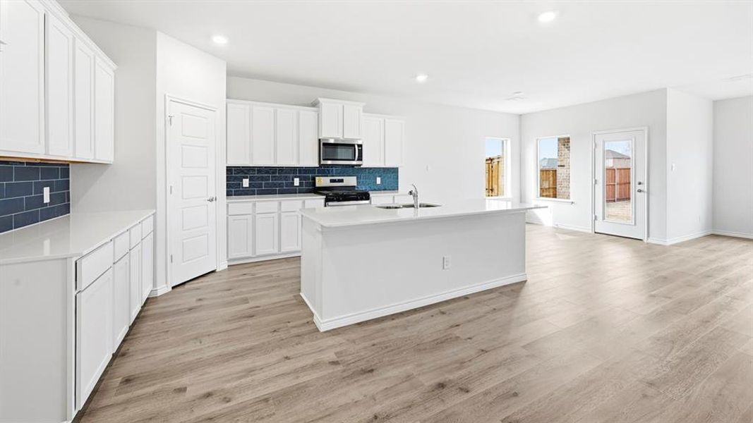 Kitchen featuring white cabinetry, a kitchen island with sink, stainless steel appliances, recessed lighting, and decorative backsplash