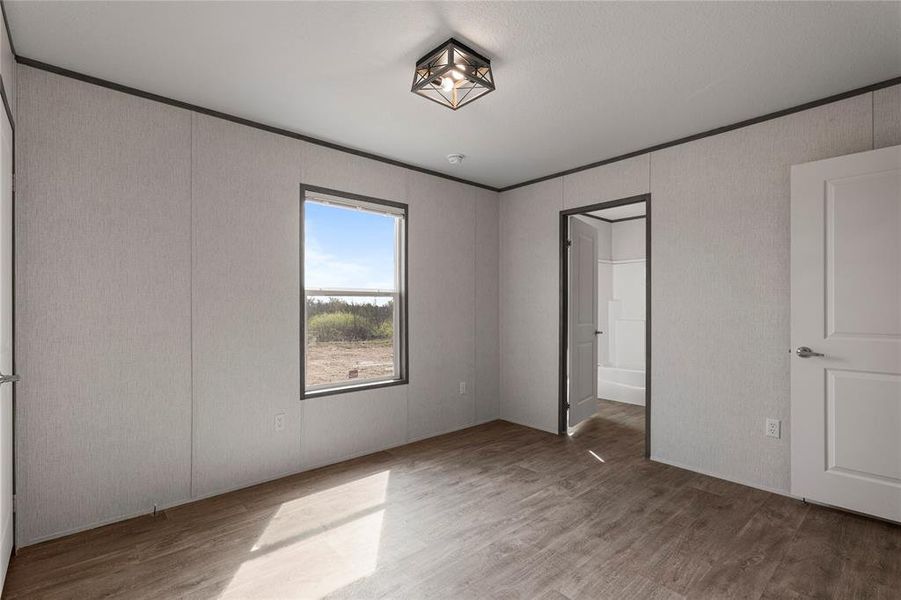 Unfurnished bedroom with ornamental molding and wood finished floors