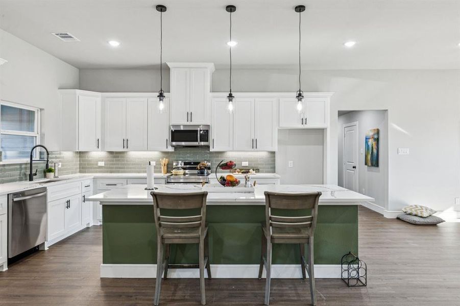 Kitchen featuring white cabinetry, stainless steel appliances, hanging light fixtures, a kitchen island, and recessed lighting