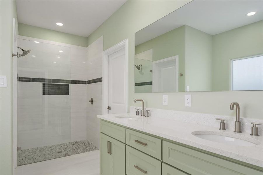 Bathroom featuring a tile shower and double sink vanity