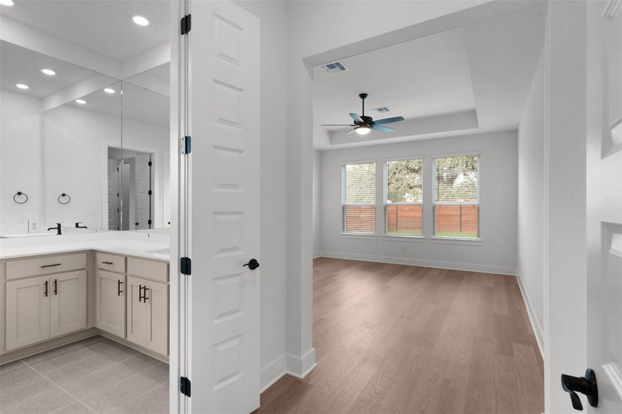 Bathroom featuring double vanity, ceiling fan, light wood-type flooring, and recessed lighting