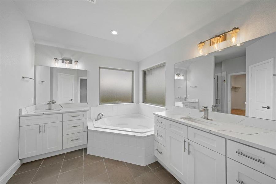 Bathroom featuring tile patterned floors, tiled bath, and double sink vanity