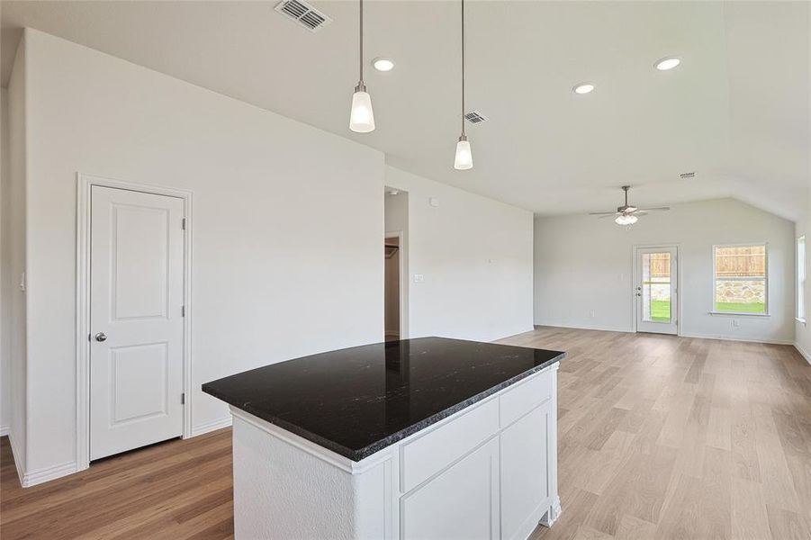 Kitchen featuring light hardwood / wood-style flooring, white cabinetry, ceiling fan, a kitchen island, and pendant lighting