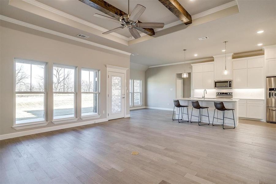 Kitchen with decorative light fixtures, a center island with sink, light hardwood / wood-style floors, and appliances with stainless steel finishes