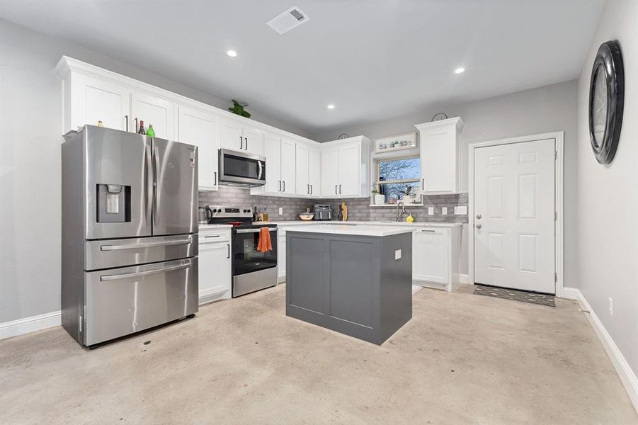 Kitchen with backsplash, stainless steel appliances, a center island, and white cabinets