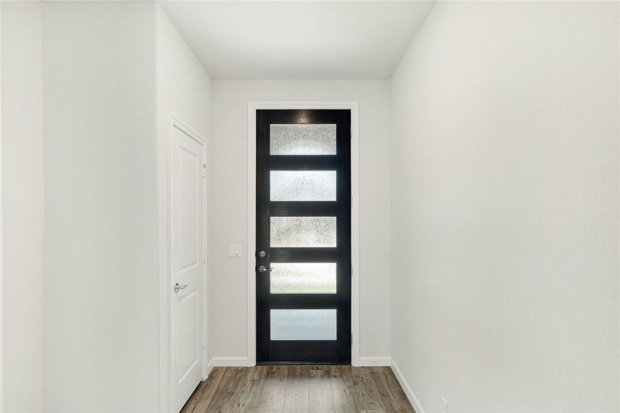Entryway with black front door featuring five frosted glass panels and wood-look flooring