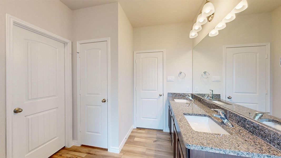 Full bathroom featuring double vanity and light wood finished floors