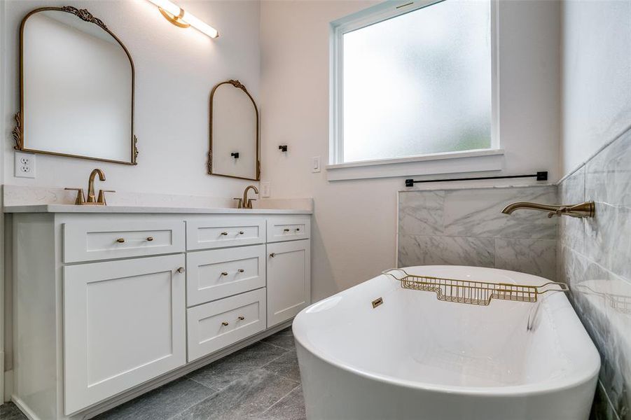 Bathroom featuring tile patterned floors, vanity, a tub, and tile walls