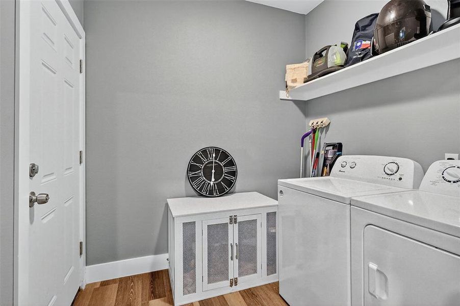 Washroom featuring washer and dryer and light wood-style flooring Washroom featuring washer and dryer and light wood-style flooring
