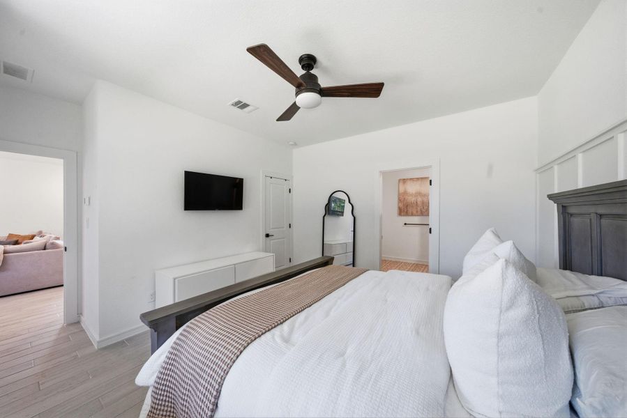 This bedroom features a modern design with  and a ceiling fan. Natural light streams in making this primary bedroom bright and inviting, perfect for relaxation.
