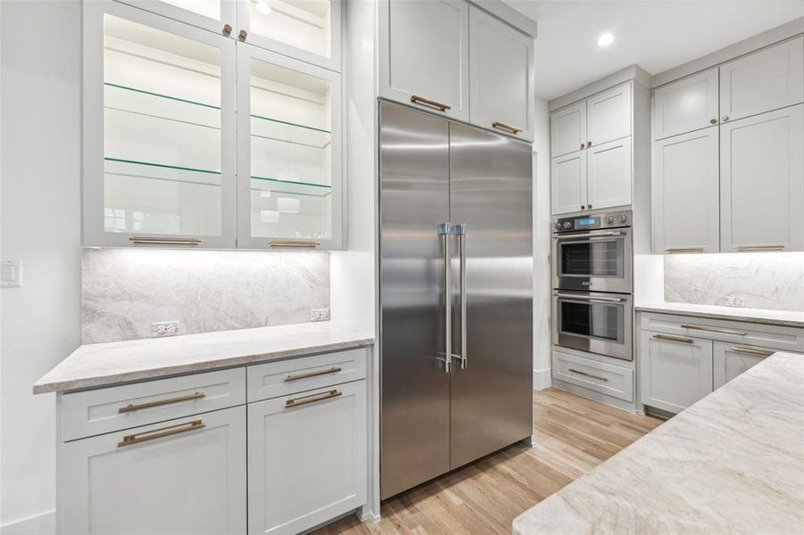 Kitchen with light hardwood / wood-style flooring, light stone countertops, tasteful backsplash, and stainless steel appliances