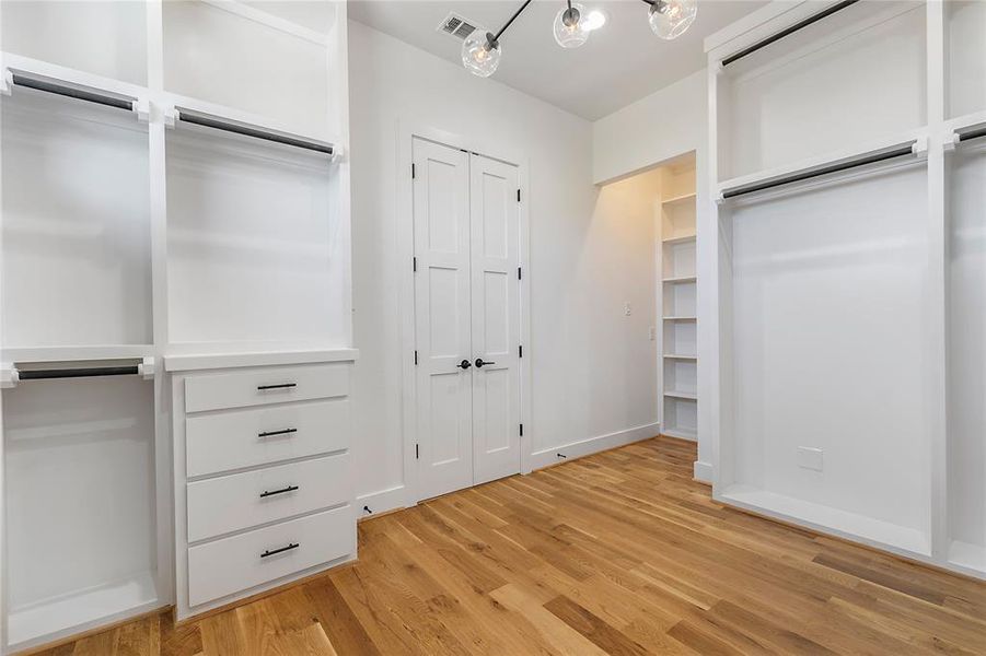 Spacious closet featuring light wood-type flooring and a chandelier