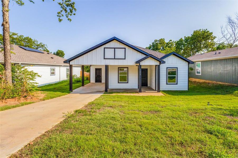 Modern inspired farmhouse featuring a front yard and a carport