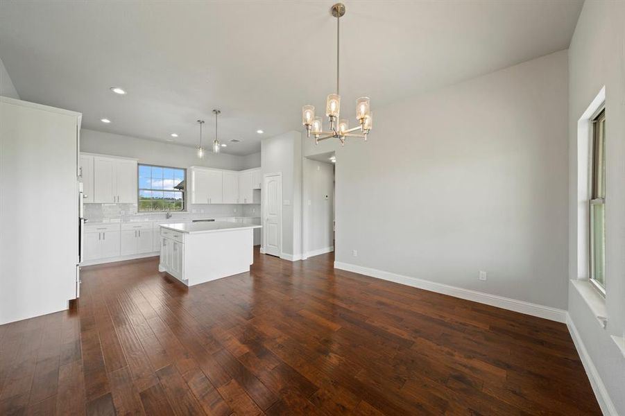 Kitchen featuring tasteful backsplash, hanging light fixtures, a kitchen island, dark hardwood / wood-style floors, and white cabinetry