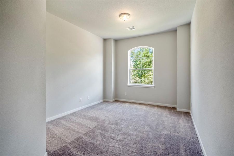 Sunlight streams into this spacious secondary bedroom.