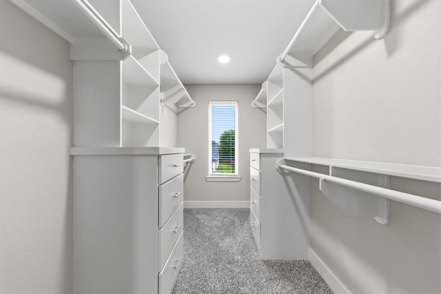 Custom designed primary walk in closet with built in drawers, shelving, and dual hanging areas. Offering exceptional storage and organization.