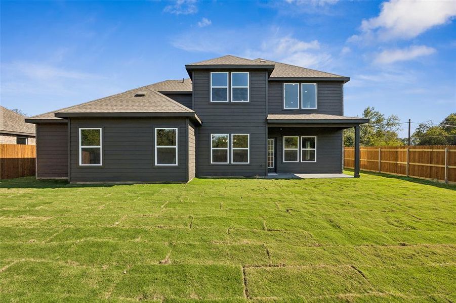 Rear view of house featuring a fenced backyard, a patio area, and roof with shingles