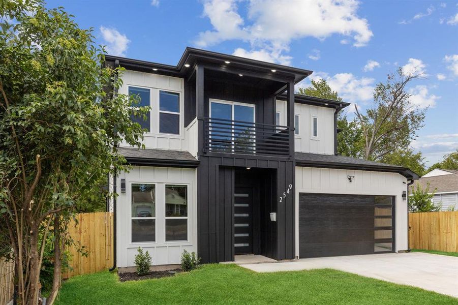 Contemporary home featuring a balcony, a garage, and a front lawn