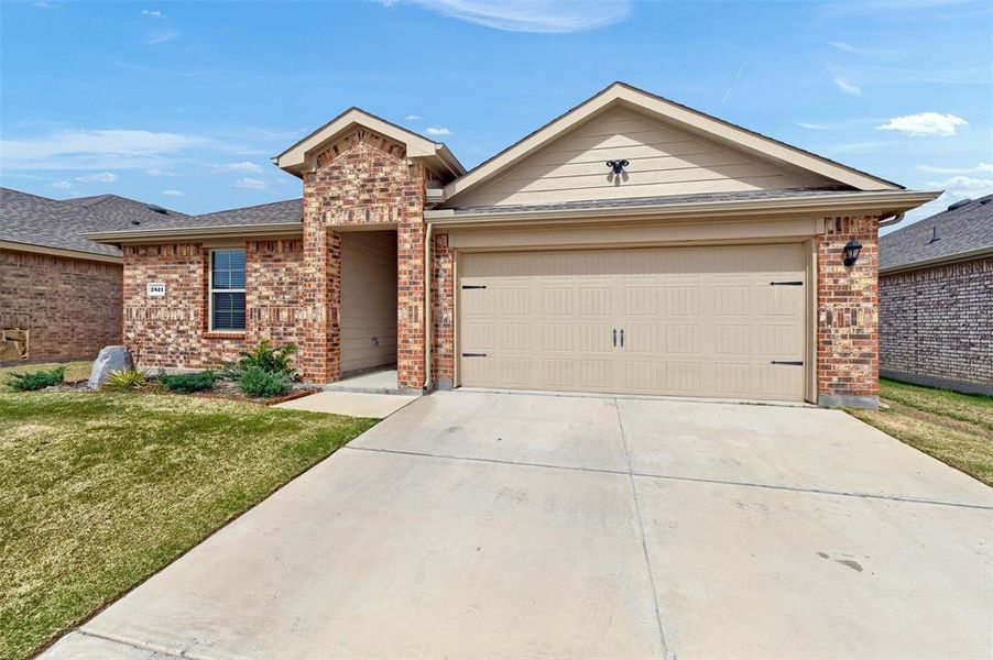Ranch-style house featuring brick siding, a front yard, driveway, and a garage