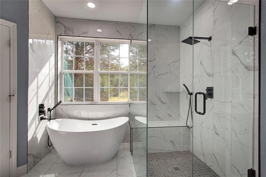 Master bathroom featuring separate shower and tub, a healthy amount of sunlight, tile patterned flooring, and tile walls