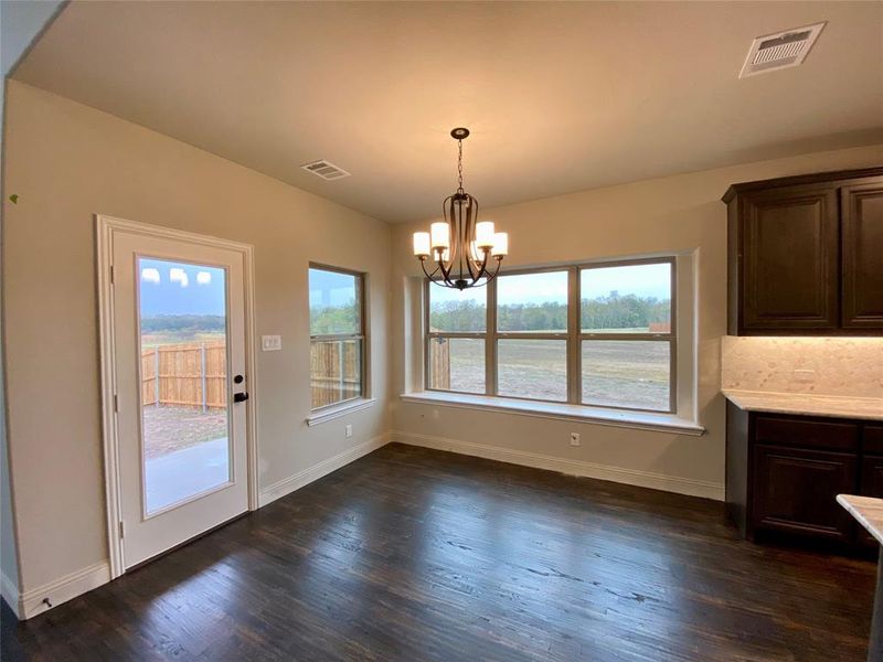 Bright dining area with a window seat and chandelier.