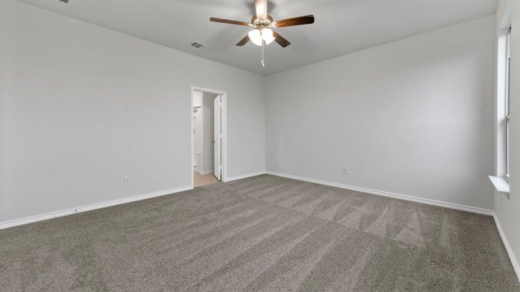 Spacious room featuring neutral carpeting, a ceiling fan with integrated lighting, and light-toned wall paint