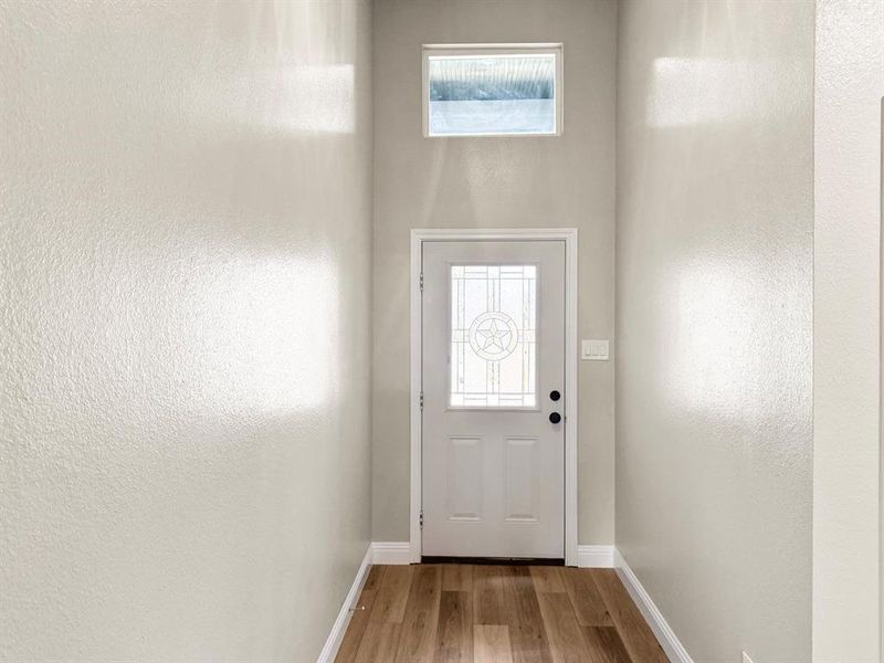 Kitchen with light stone counters, a kitchen island with sink, light wood-type flooring, vaulted ceiling, and hanging light fixtures