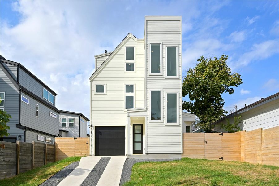 Contemporary house featuring a garage, fence, a chimney, and driveway Contemporary house featuring a garage, fence, a chimney, and driveway