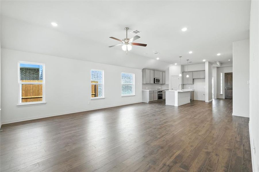 Unfurnished living room with dark wood-type flooring, recessed lighting, ceiling fan, and lofted ceiling Unfurnished living room with dark wood-type flooring, recessed lighting, ceiling fan, and lofted ceiling