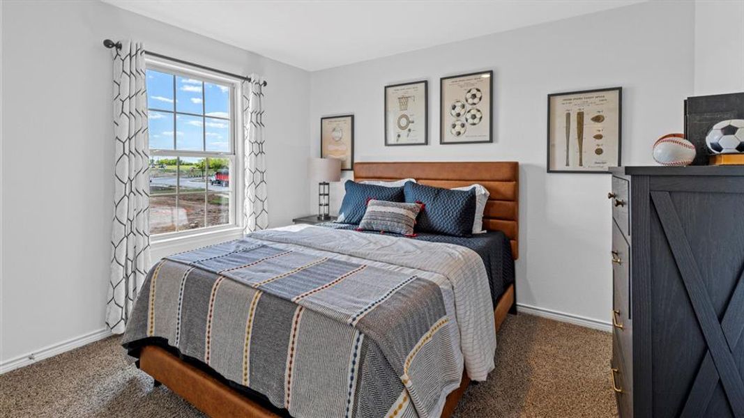 Carpeted bedroom featuring a large window with white trim, white walls, and a warm-toned headboard Carpeted bedroom featuring a large window with white trim, white walls, and a warm-toned headboard